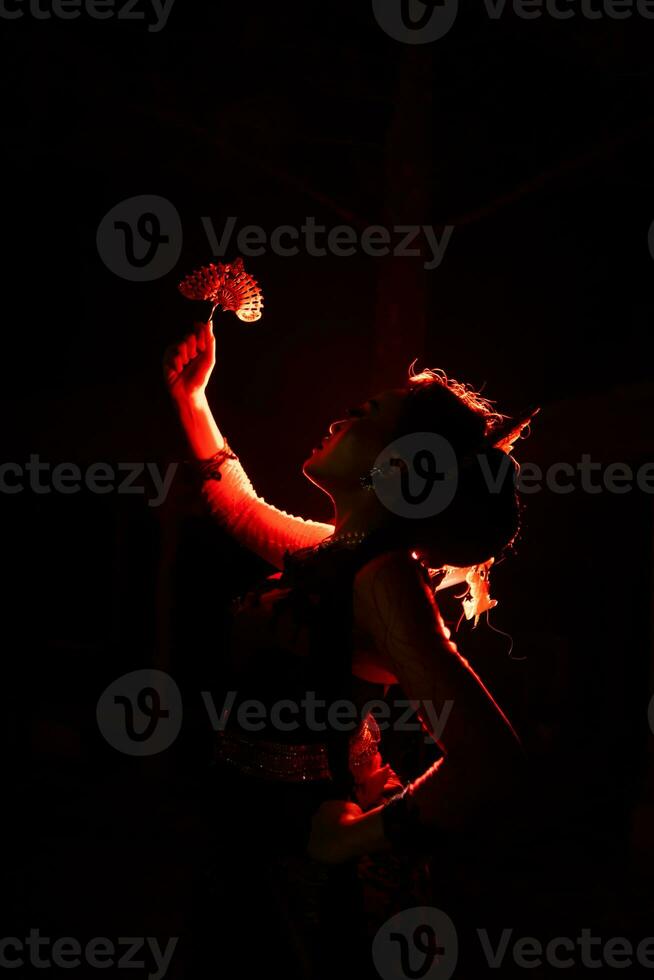 the silhouette of a female dancer holding jewelry that looks like a reflection reflecting in the dim light photo