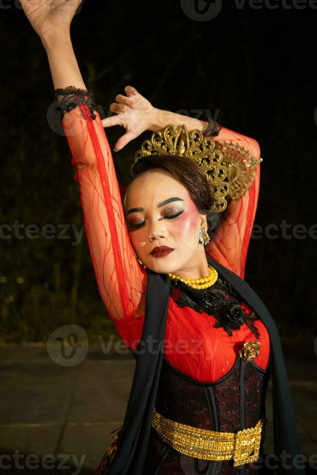 a Balinese woman wears heavy makeup with rosy red lips and sharp hair when posing photo