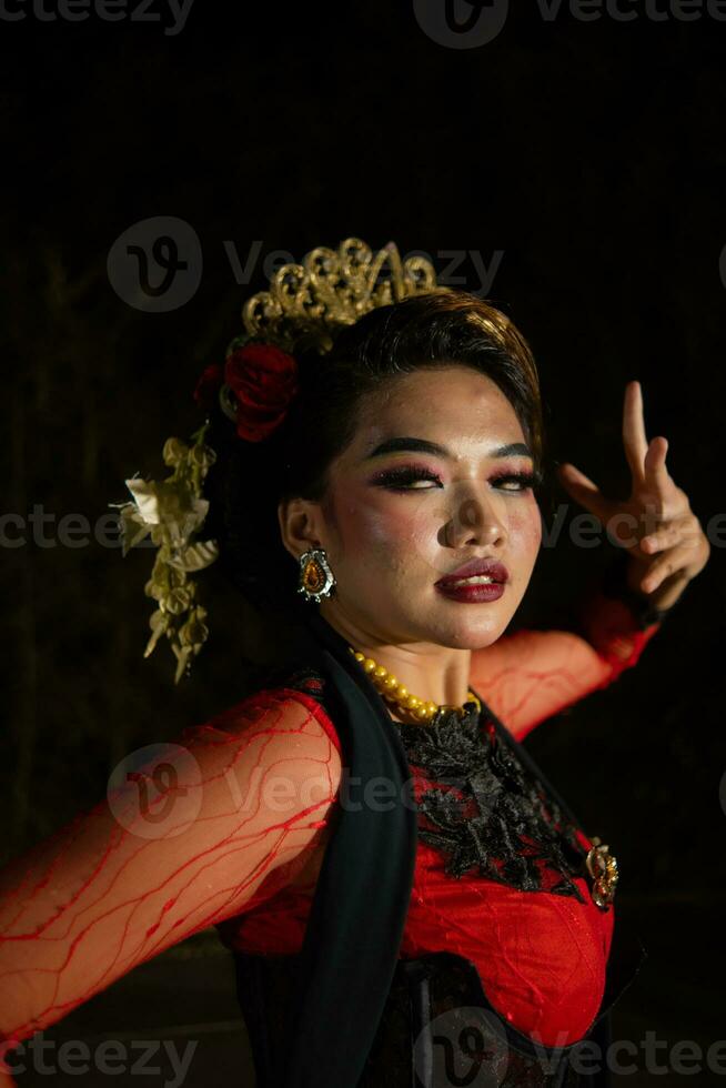 cerca arriba de un indonesio mujer en un balinés bailarín disfraz posando muy hermosamente a noche foto