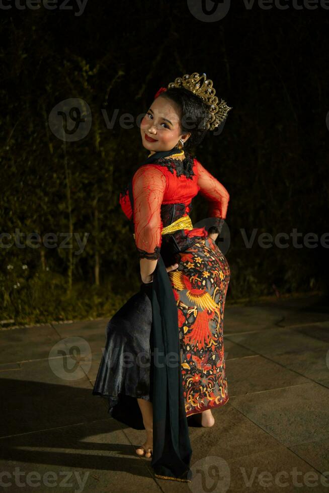 a Vietnamese dancer wearing a red costume and gold jewelry on stage at night photo