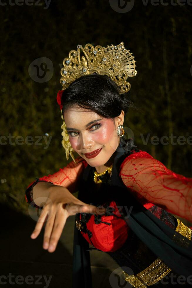 a Javanese dancer dancing with gold accessories and a face full of makeup photo