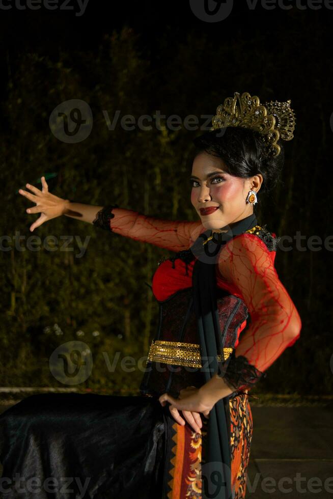 a Javanese dancer dancing with gold accessories and a face full of makeup photo