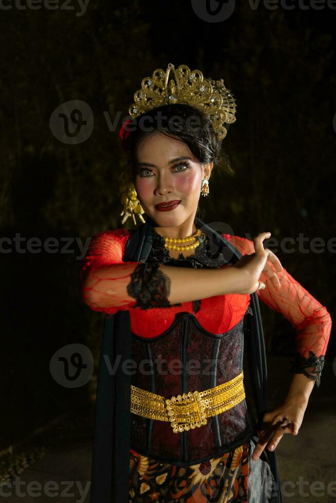 An Indonesian dancer in red clothes and a black scarf poses with very curly and beautiful fingers photo