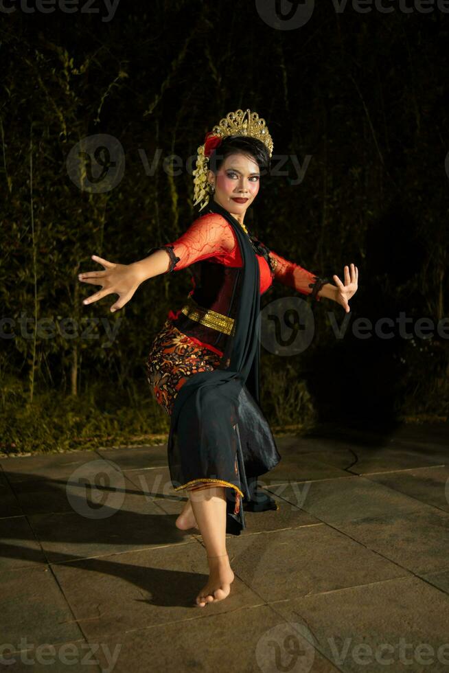 a Javanese dancer dancing with gold accessories and a face full of makeup photo