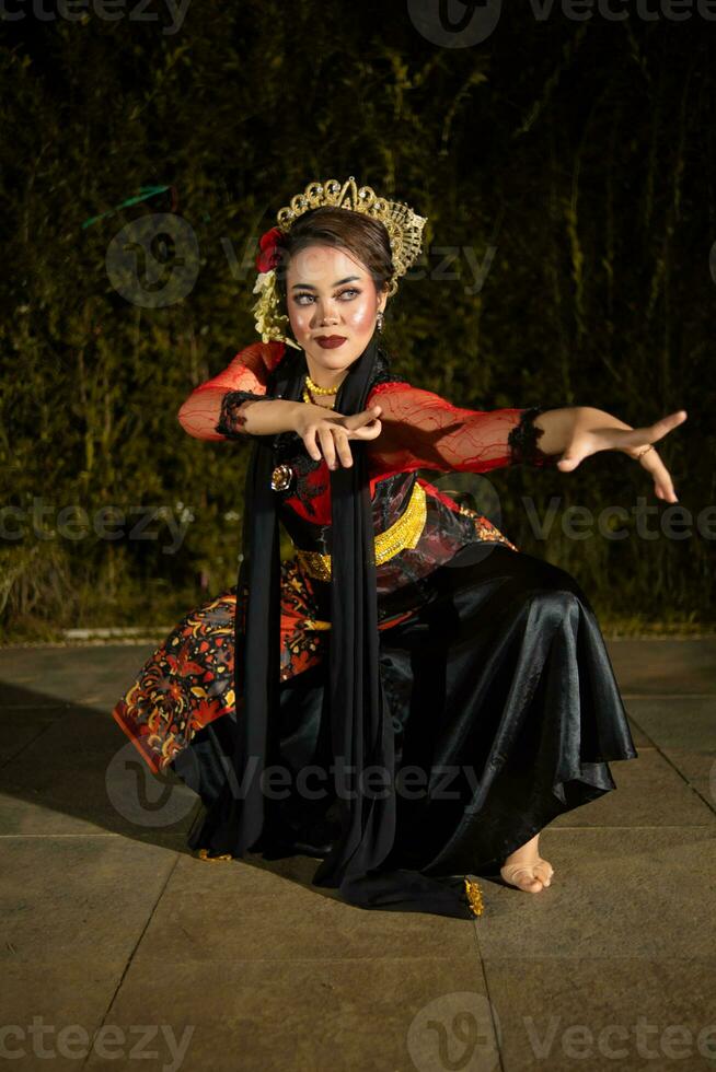 An Asian dancer in a red costume poses very flexibly on a stage photo