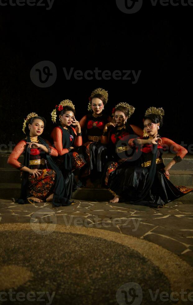 a group of dancers attract attention in striking red costumes and sit together photo