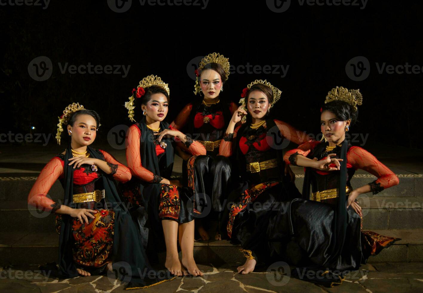 a group of dancers attract attention in striking red costumes and sit together photo