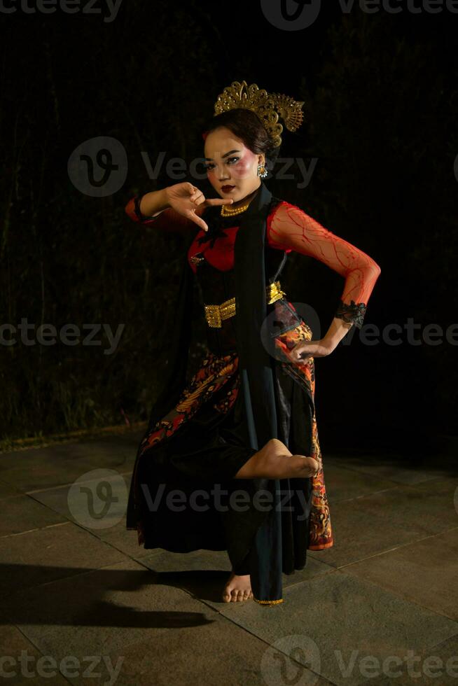 a woman wearing a red dress and black shawl while dancing in front of the audience photo