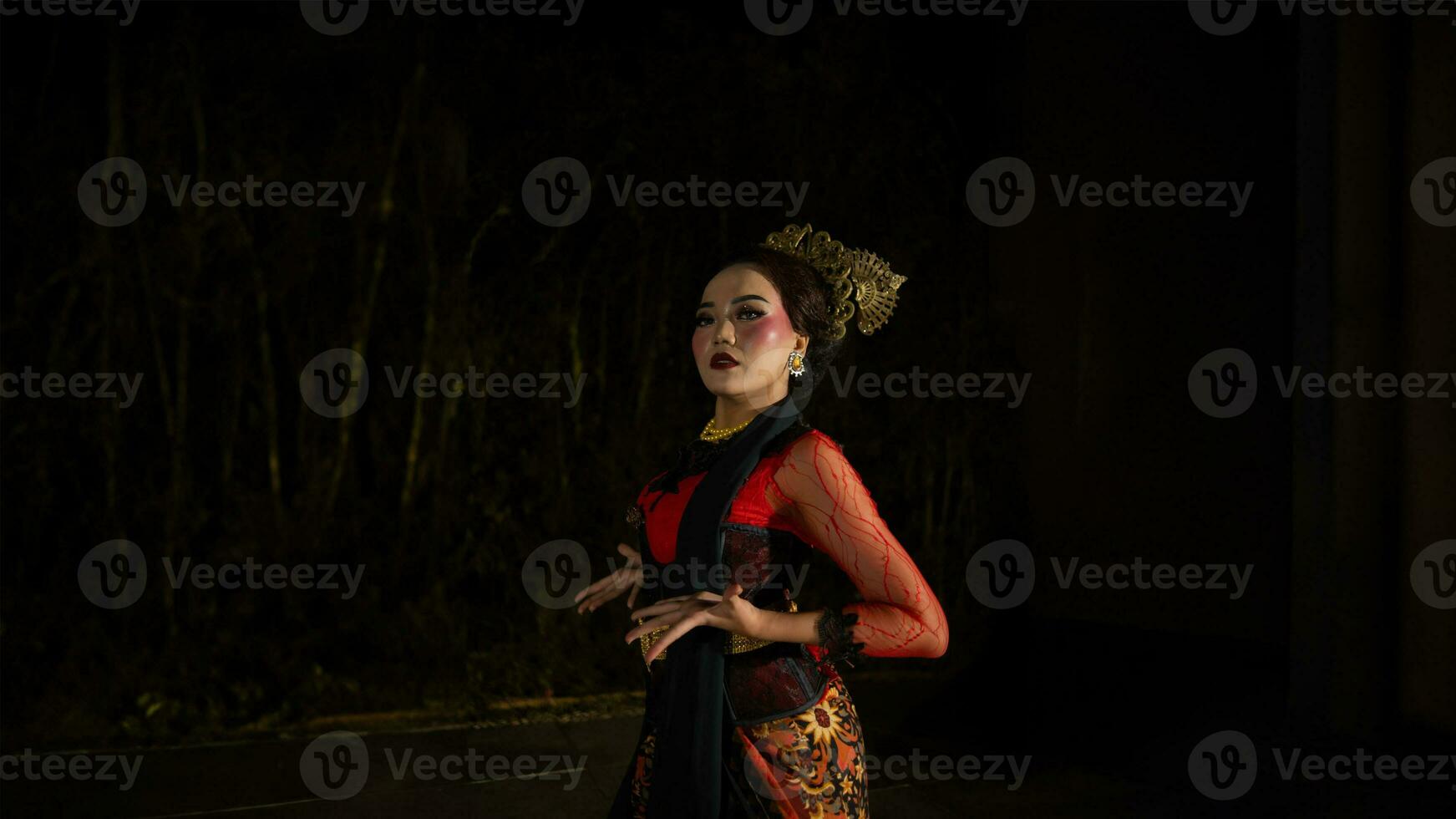 un javanés bailarín vestido en tradicional rojo ropa encantado el audiencia con su agraciado movimientos ese mezclado con el melodía foto