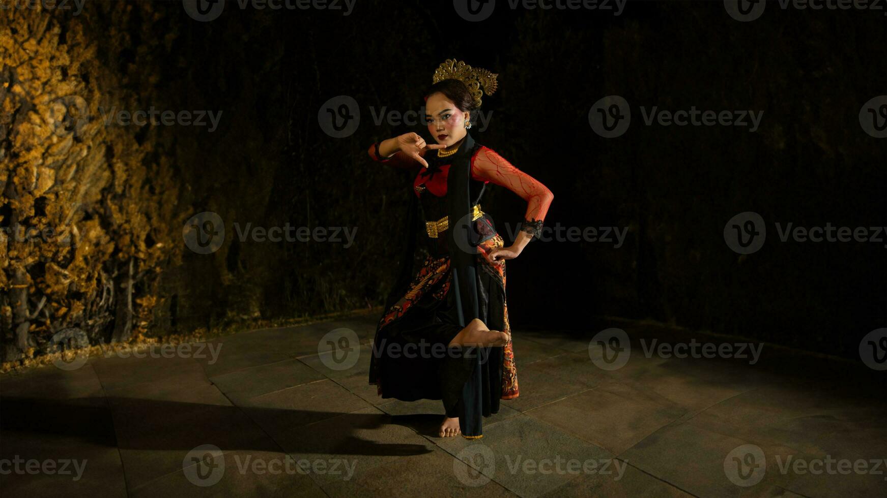 A Sundanese dancer wears a beautiful sparkling red costume and dances with a passionate expression photo