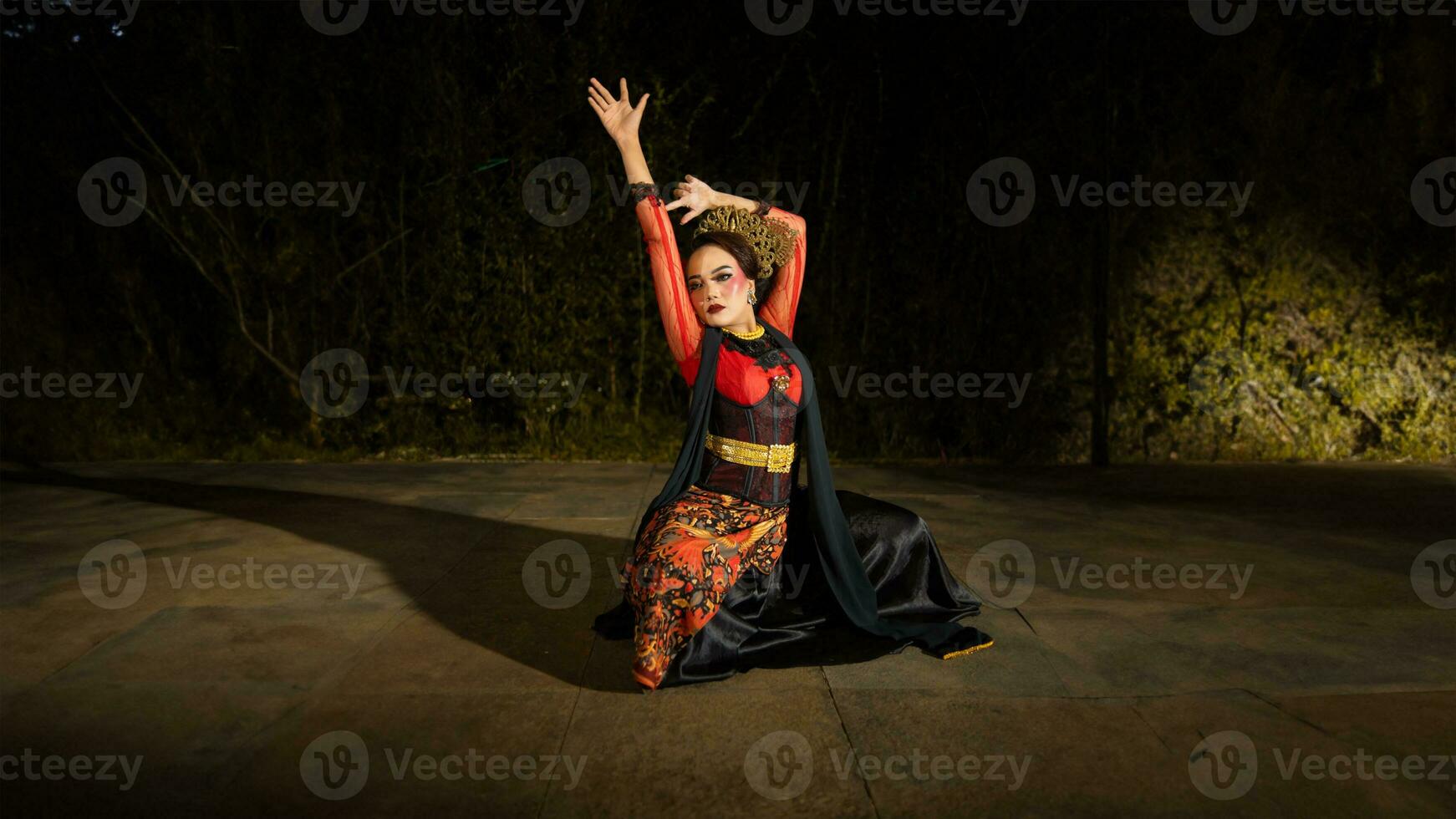 A Sundanese dancer wears a beautiful sparkling red costume and dances with a passionate expression photo