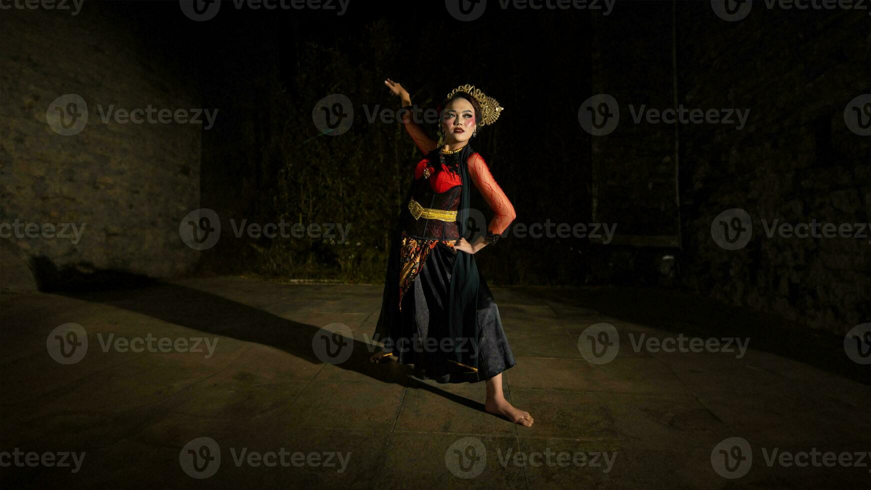 an Indonesian dancer wearing jewelry that shines under the spotlight of the stage lights adds to the brilliance of the performance photo