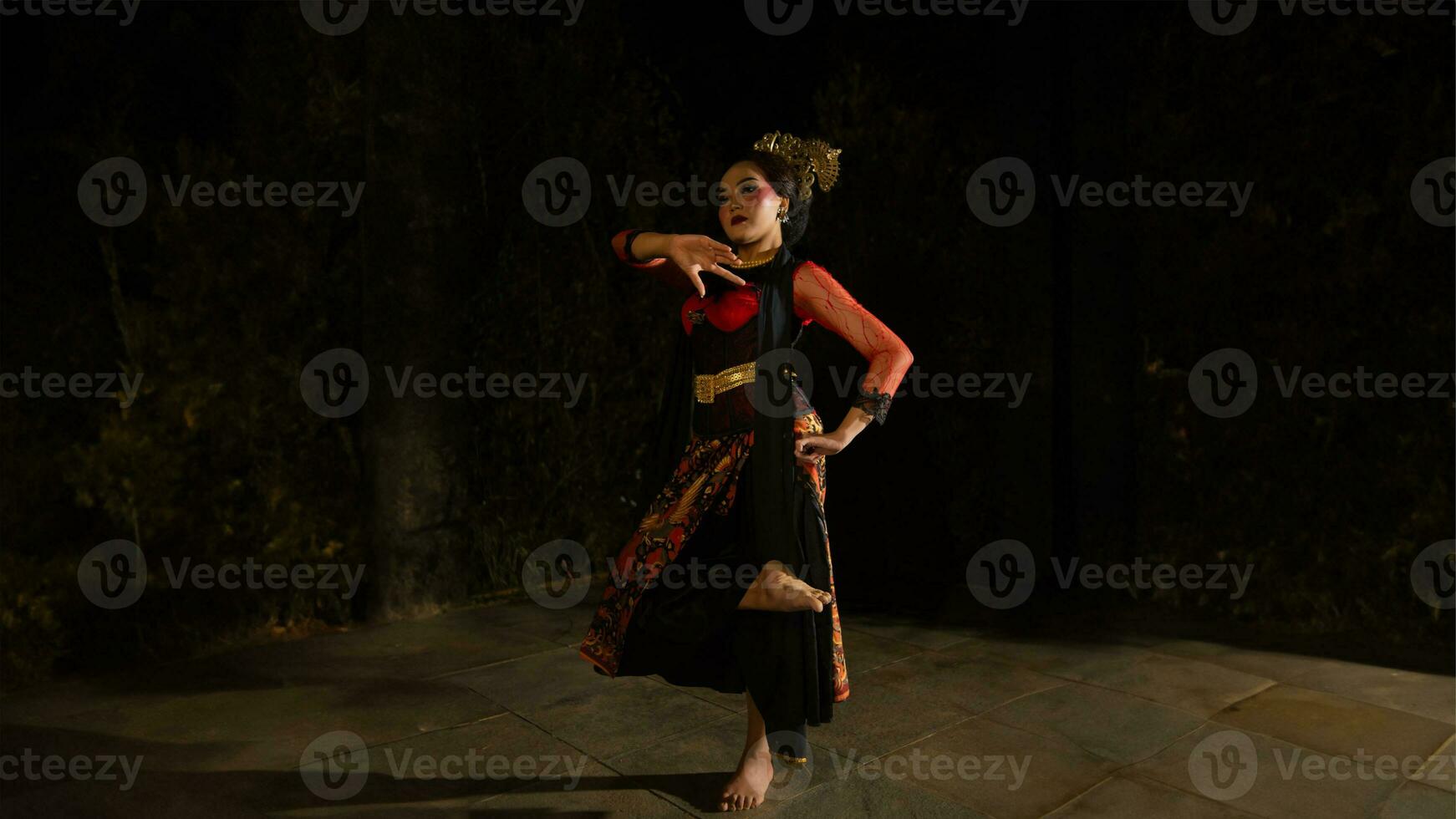 A Sundanese dancer wears a beautiful sparkling red costume and dances with a passionate expression photo