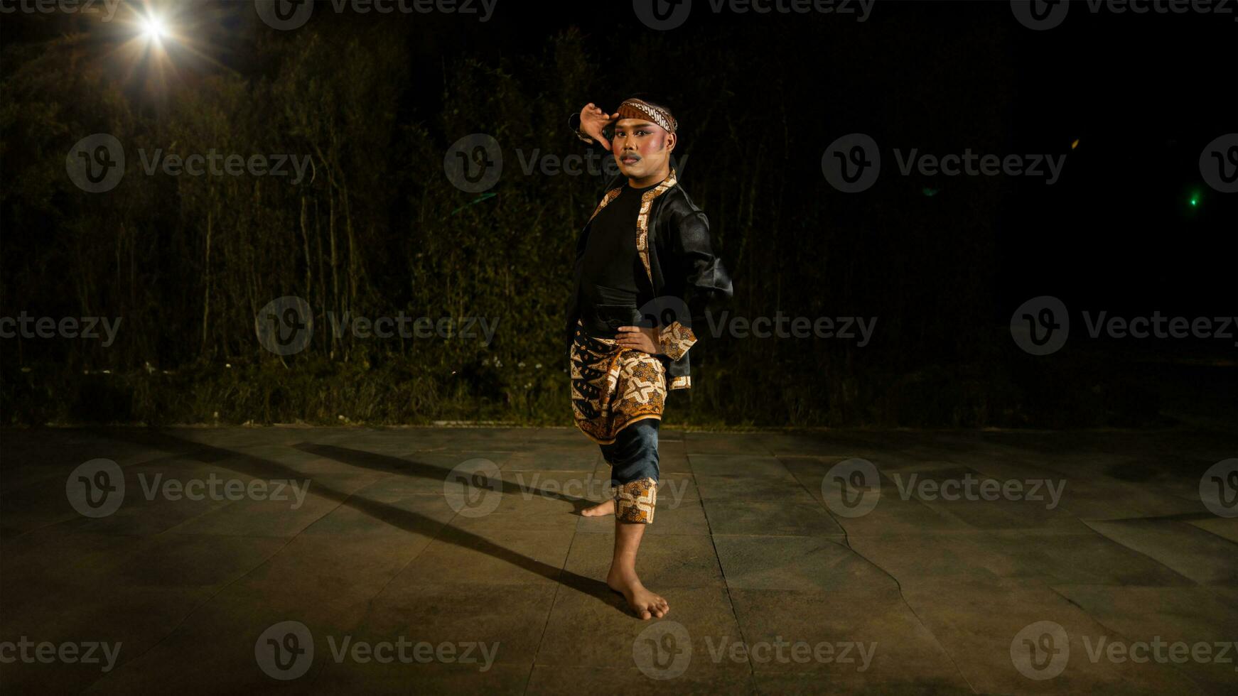 an Indonesian man dances with determination and skill while wearing a black costume on stage photo
