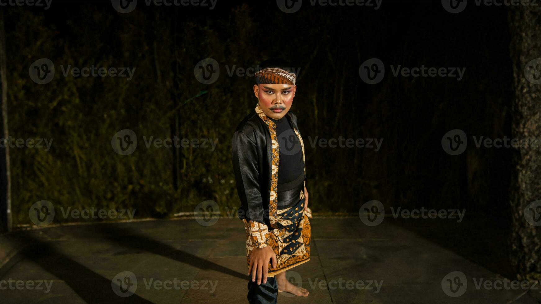 an Indonesian man dances with determination and skill while wearing a black costume on stage photo