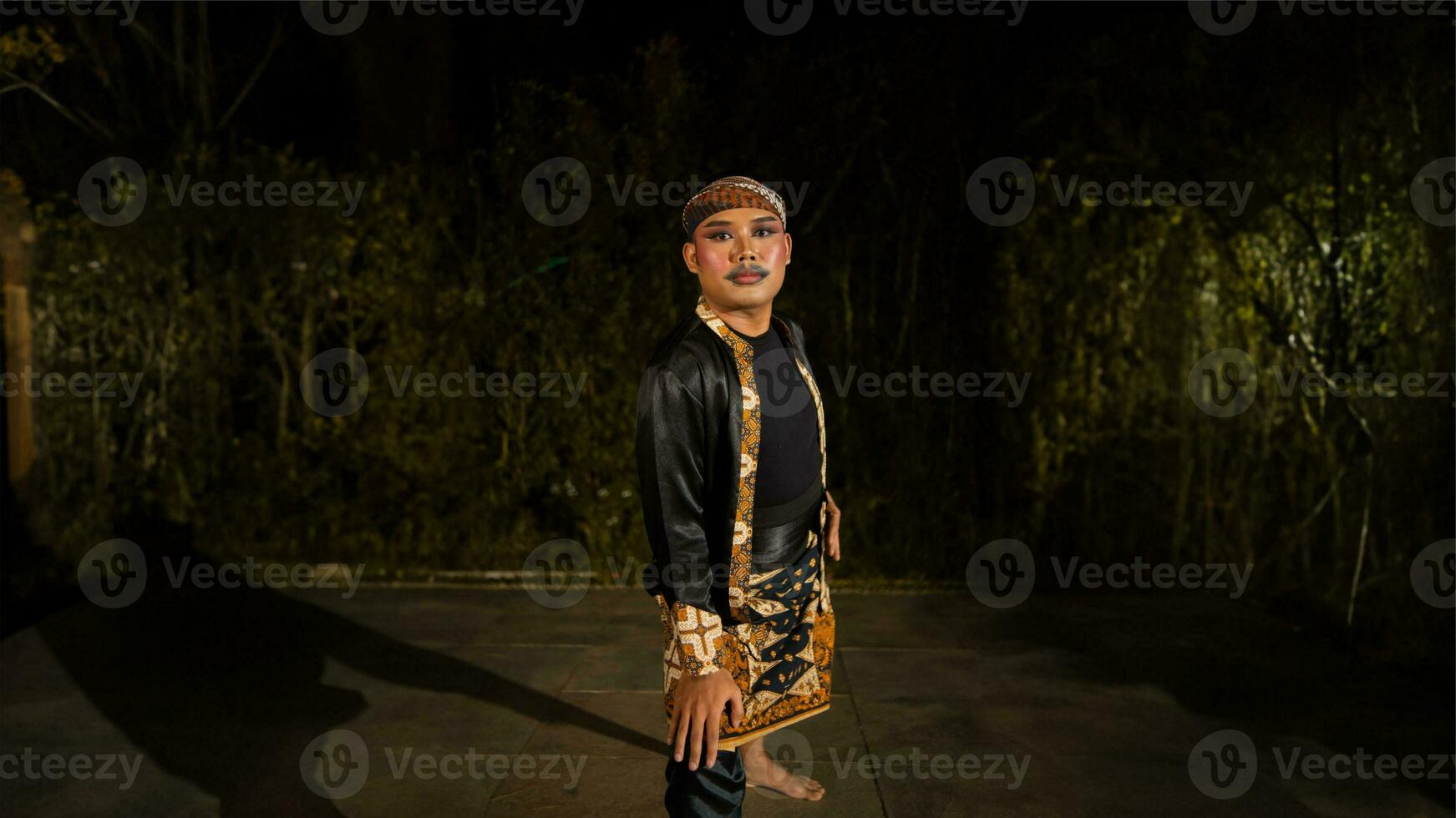 an Indonesian man dances with determination and skill while wearing a black costume on stage photo