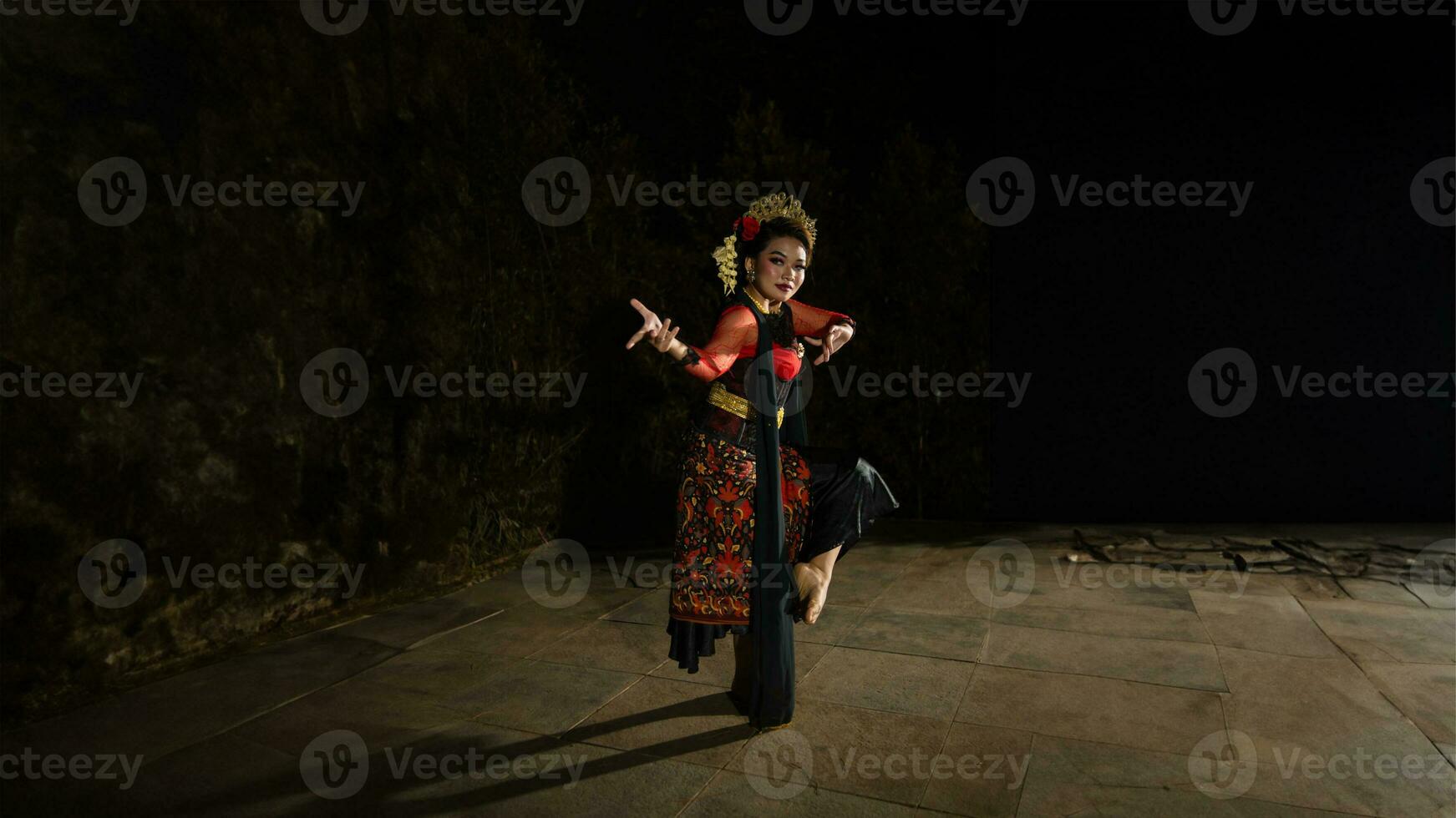 A Sundanese dancer wears a beautiful sparkling red costume and dances with a passionate expression photo