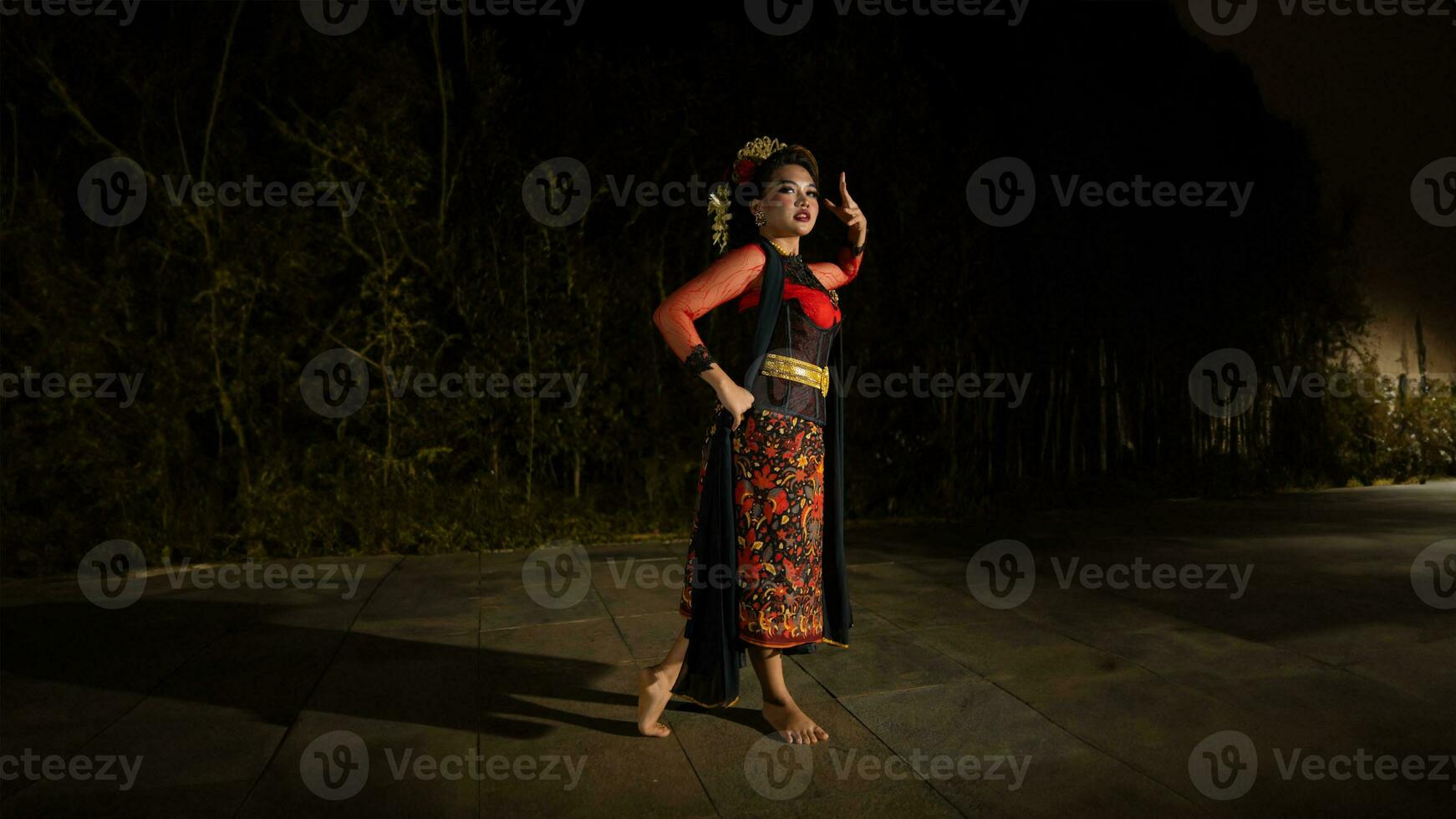 an Asian dancer dancing in front of the yard in a red costume photo