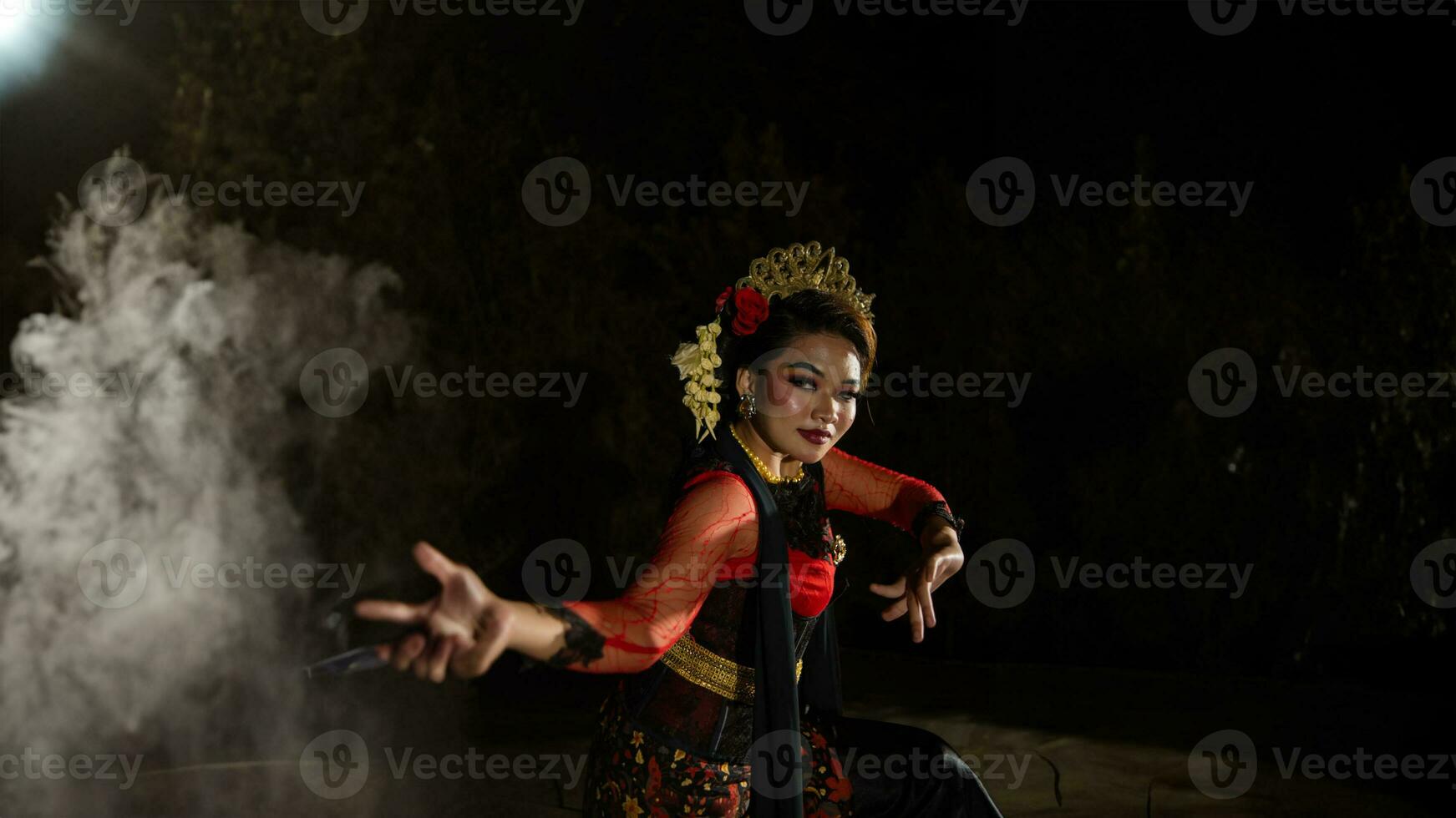 un javanés bailarín vestido en tradicional rojo ropa encantado el audiencia con su agraciado movimientos ese mezclado con el melodía foto