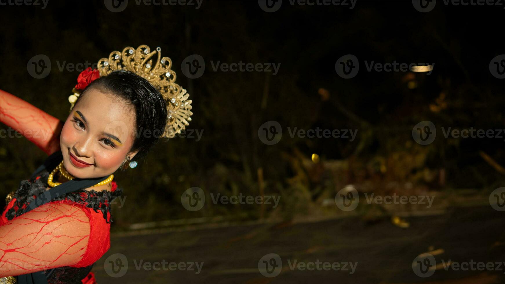 an Indonesian dancer radiates charm that attracts the attention of the audience throughout the performance with her red dress photo