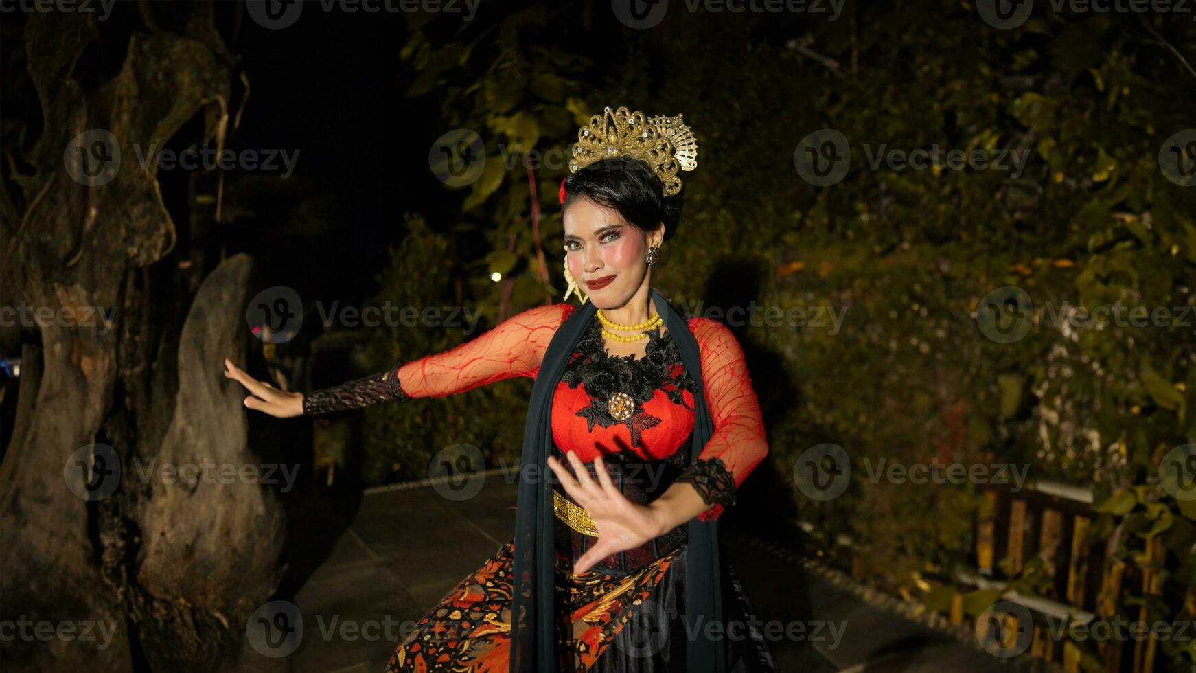a Balinese dancer wearing gold jewelry and dancing with confidence on the stage photo