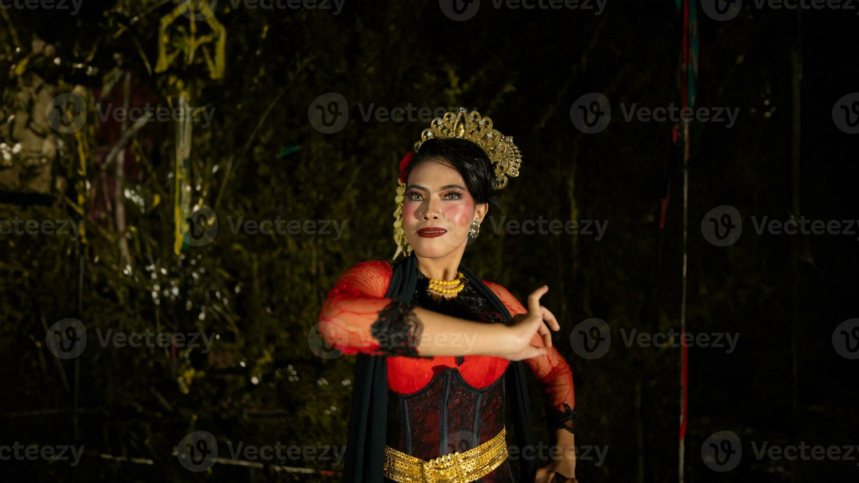 a Balinese dancer wearing gold jewelry and dancing with confidence on the stage photo