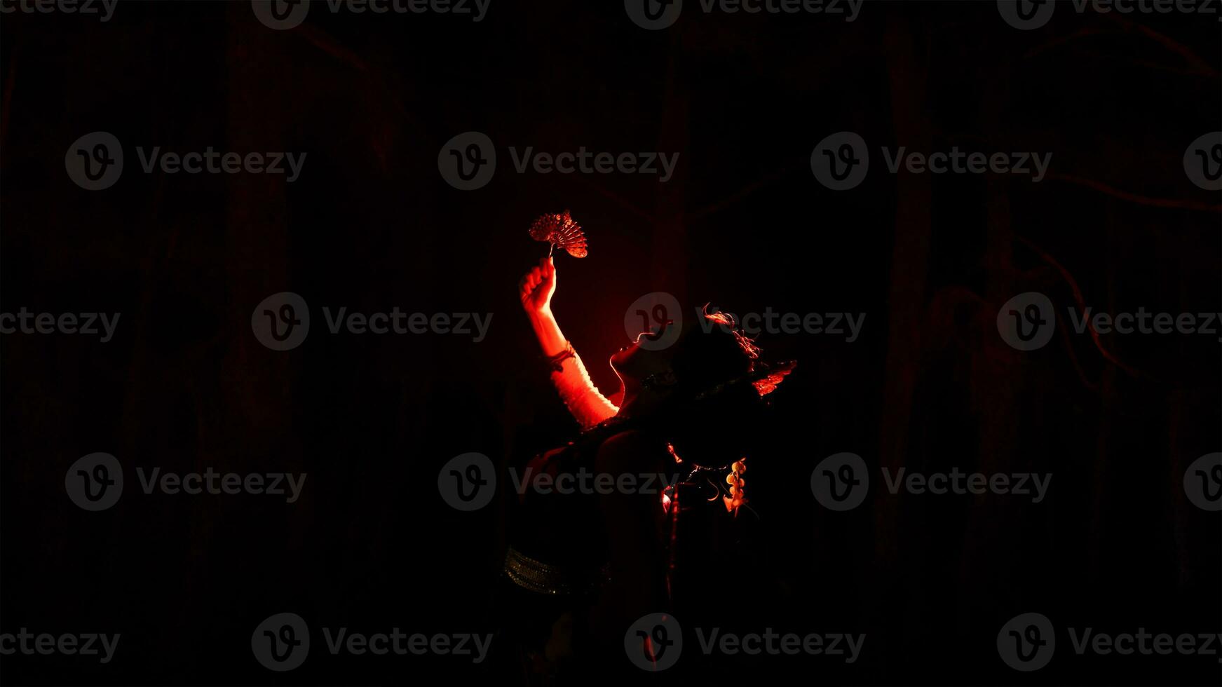 silueta de un hembra bailarín participación joyería en el medio de el quietud de el noche con rojo ligero foto