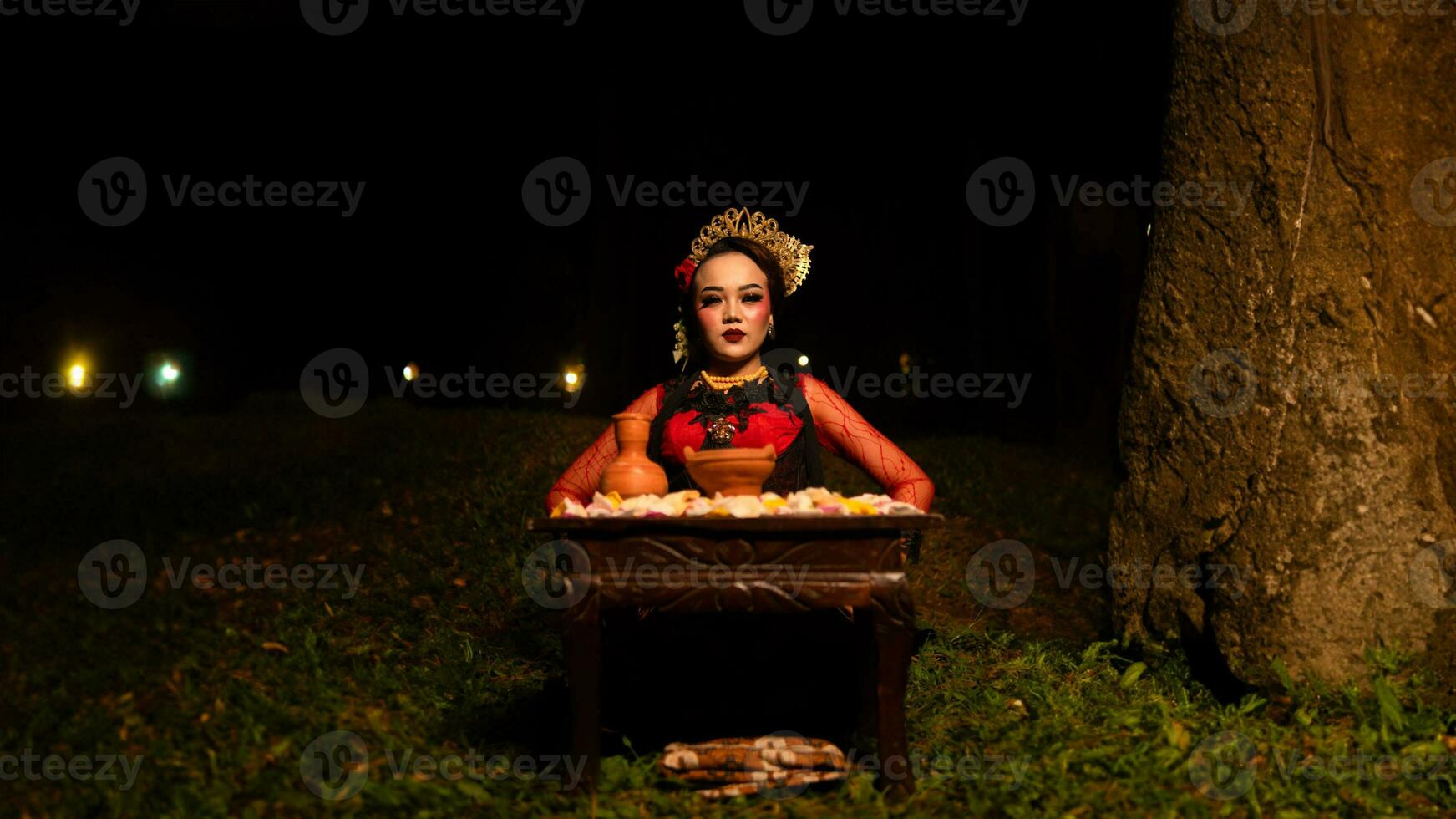 a female dancer looks focused on her ritual with a peaceful facial expression in front of offerings that look fresh and lively photo