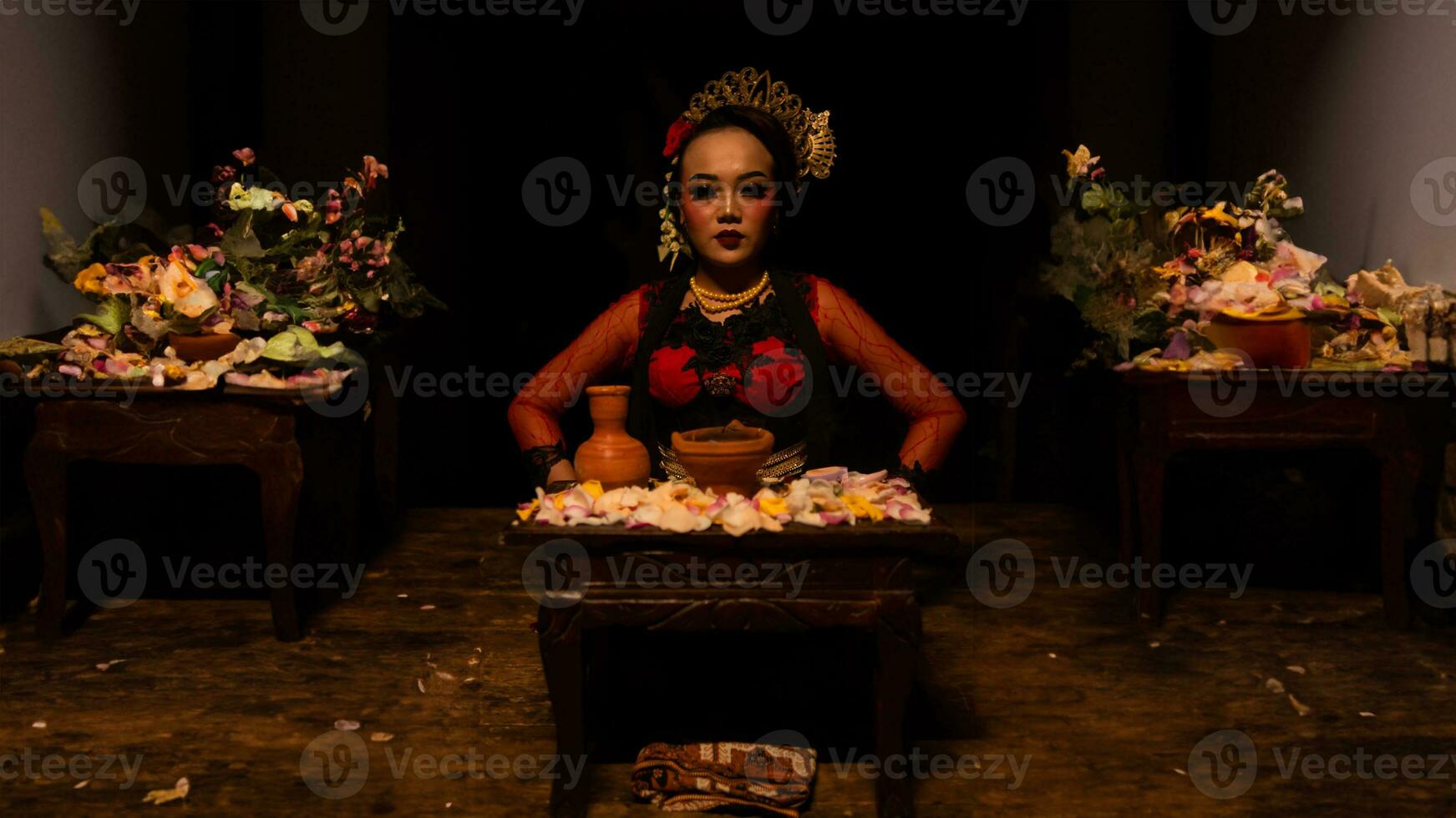 un hembra bailarín se sienta graciosamente y comienza su ritual en frente de hermosa ofrendas foto