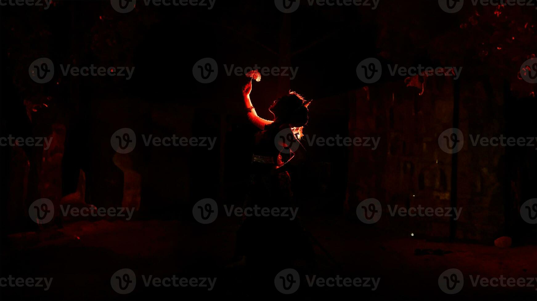 the silhouette of a female dancer holding jewelry that looks like a reflection reflecting in the dim light photo