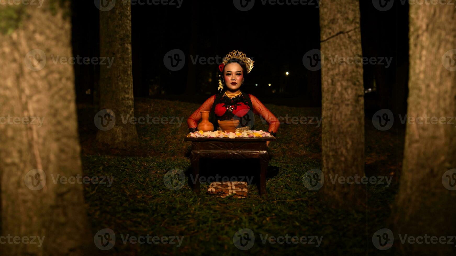 un hembra bailarín quien mira hermosa en un rojo disfraz realiza un ritual ese irradia un aura de belleza y pureza foto