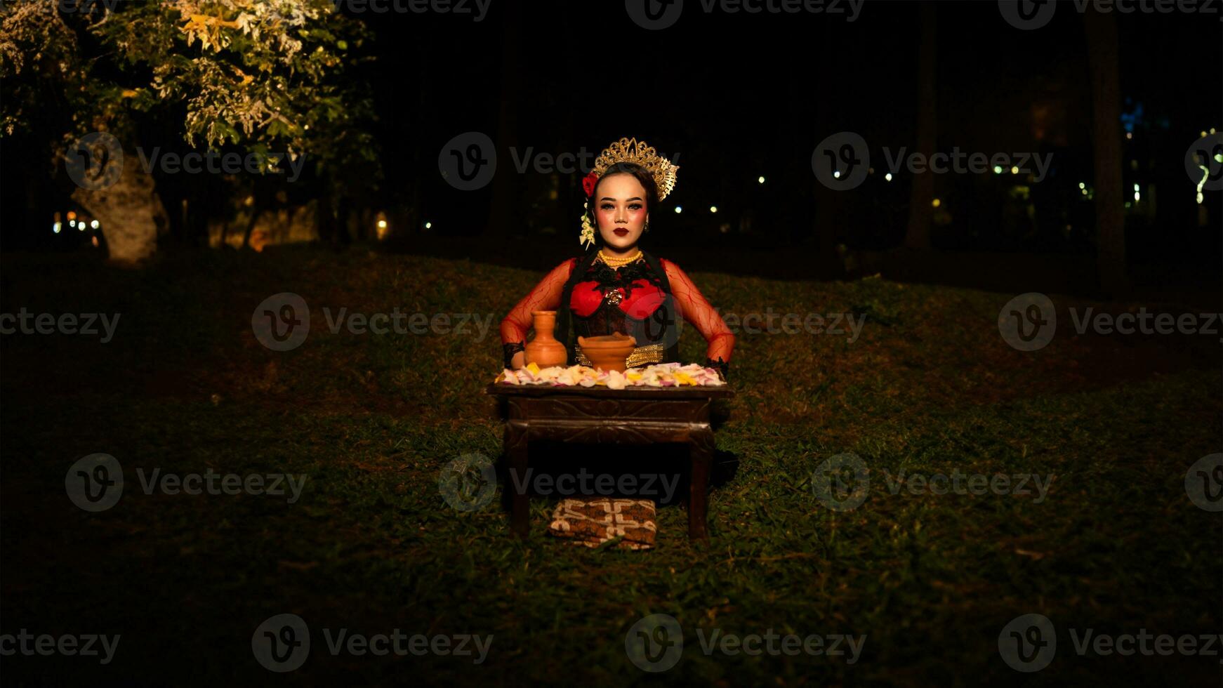 a female dancer looks focused on her ritual with a peaceful facial expression in front of offerings that look fresh and lively photo