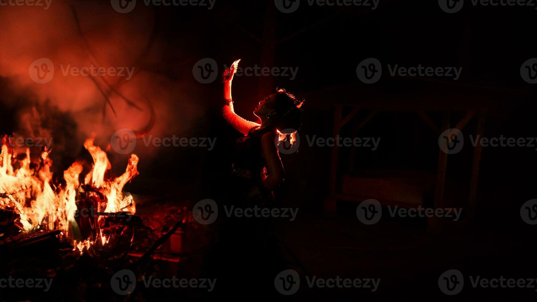 the silhouette of a woman looking at her jewelry with a face full of sadness and the fire burning around her photo