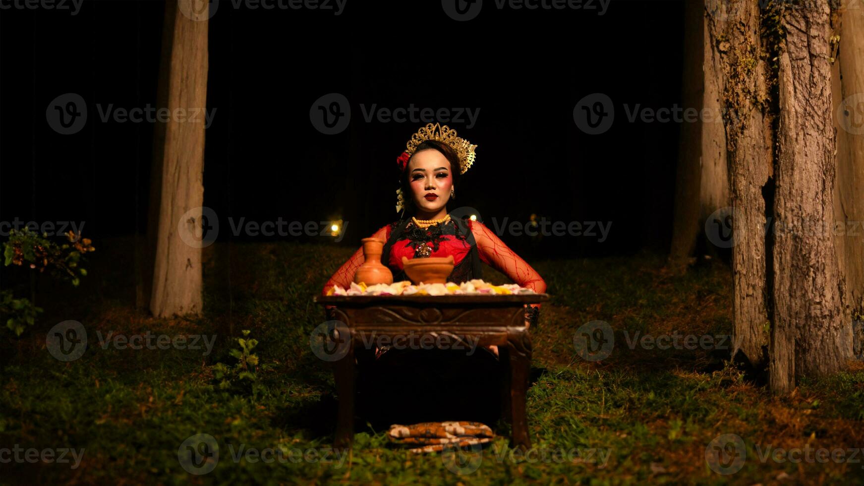 a female dancer looks focused on her ritual with a peaceful facial expression in front of offerings that look fresh and lively photo