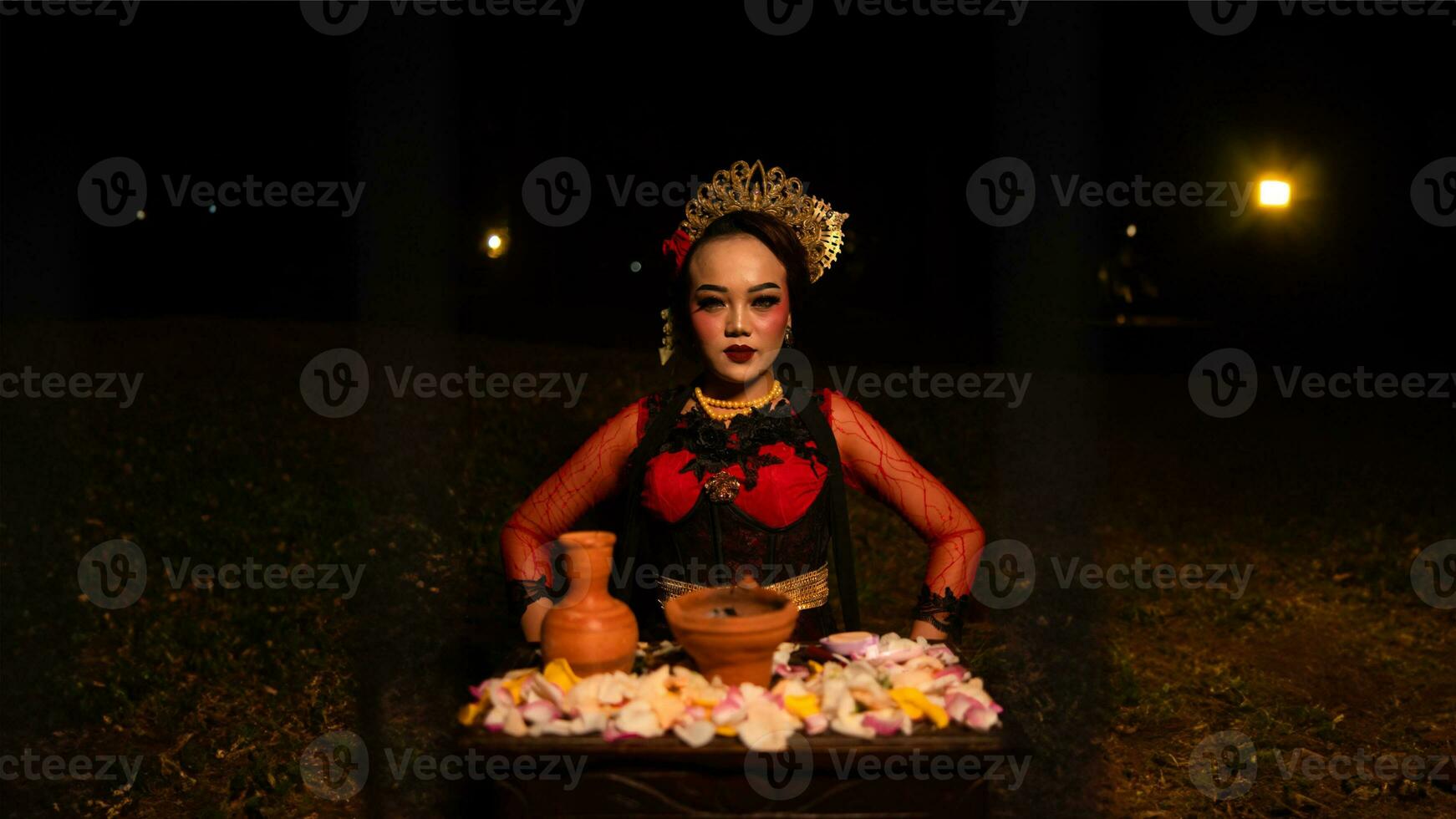 a female dancer looks focused on her ritual with a peaceful facial expression in front of offerings that look fresh and lively photo