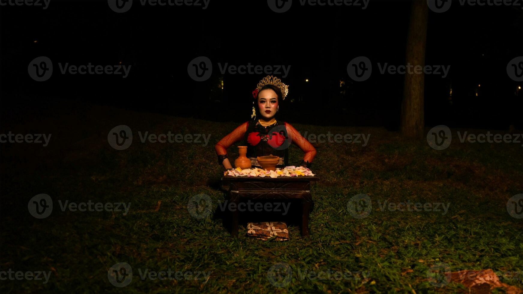 a female dancer who looks beautiful in a red costume performs a ritual that radiates an aura of beauty and purity photo