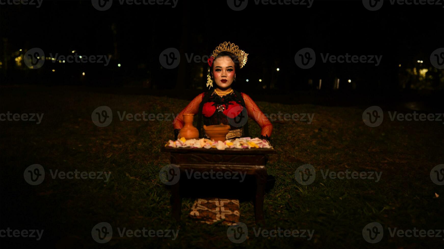 a female dancer who looks beautiful in a red costume performs a ritual that radiates an aura of beauty and purity photo