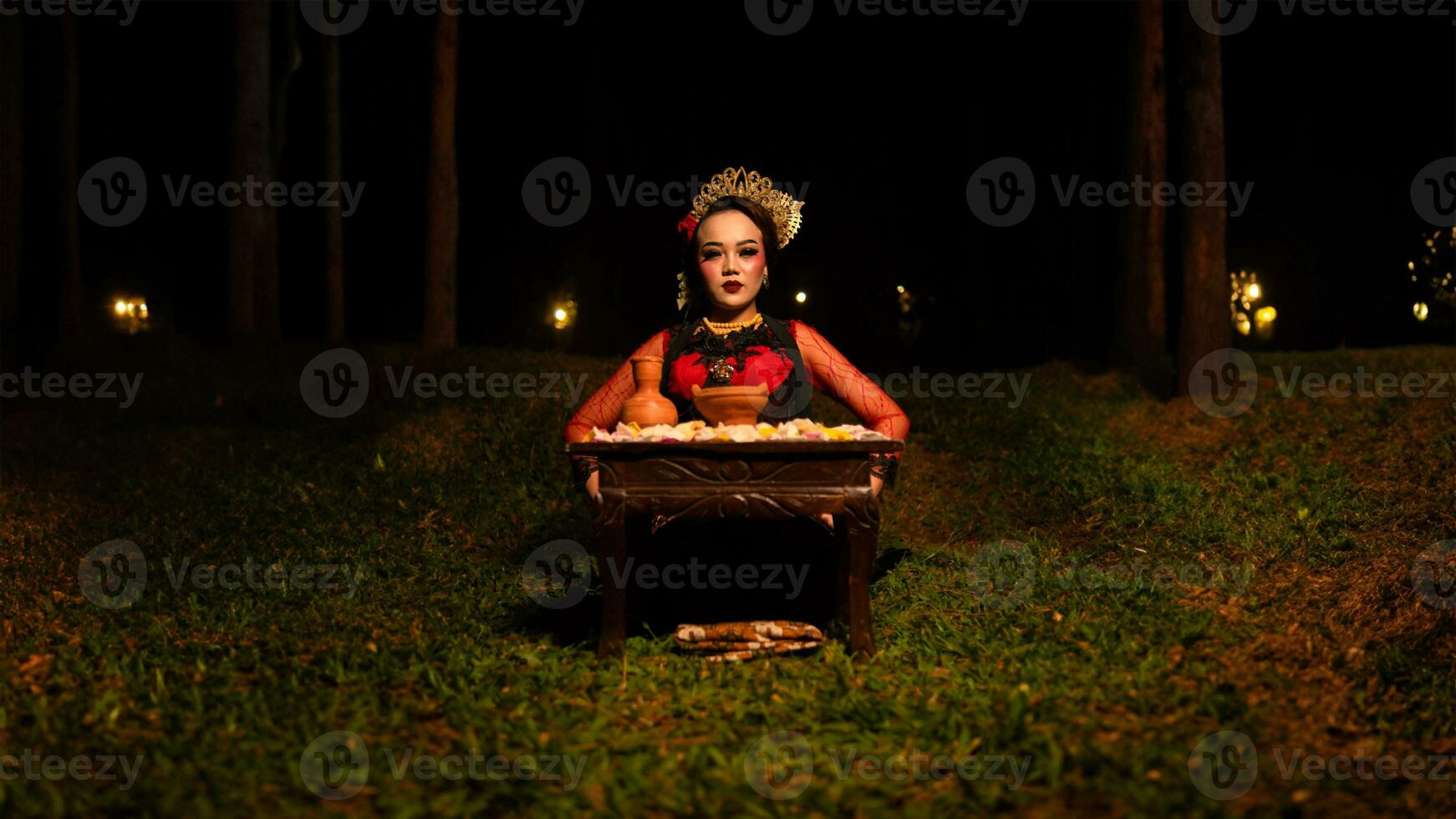 a female dancer looks focused on her ritual with a peaceful facial expression in front of offerings that look fresh and lively photo