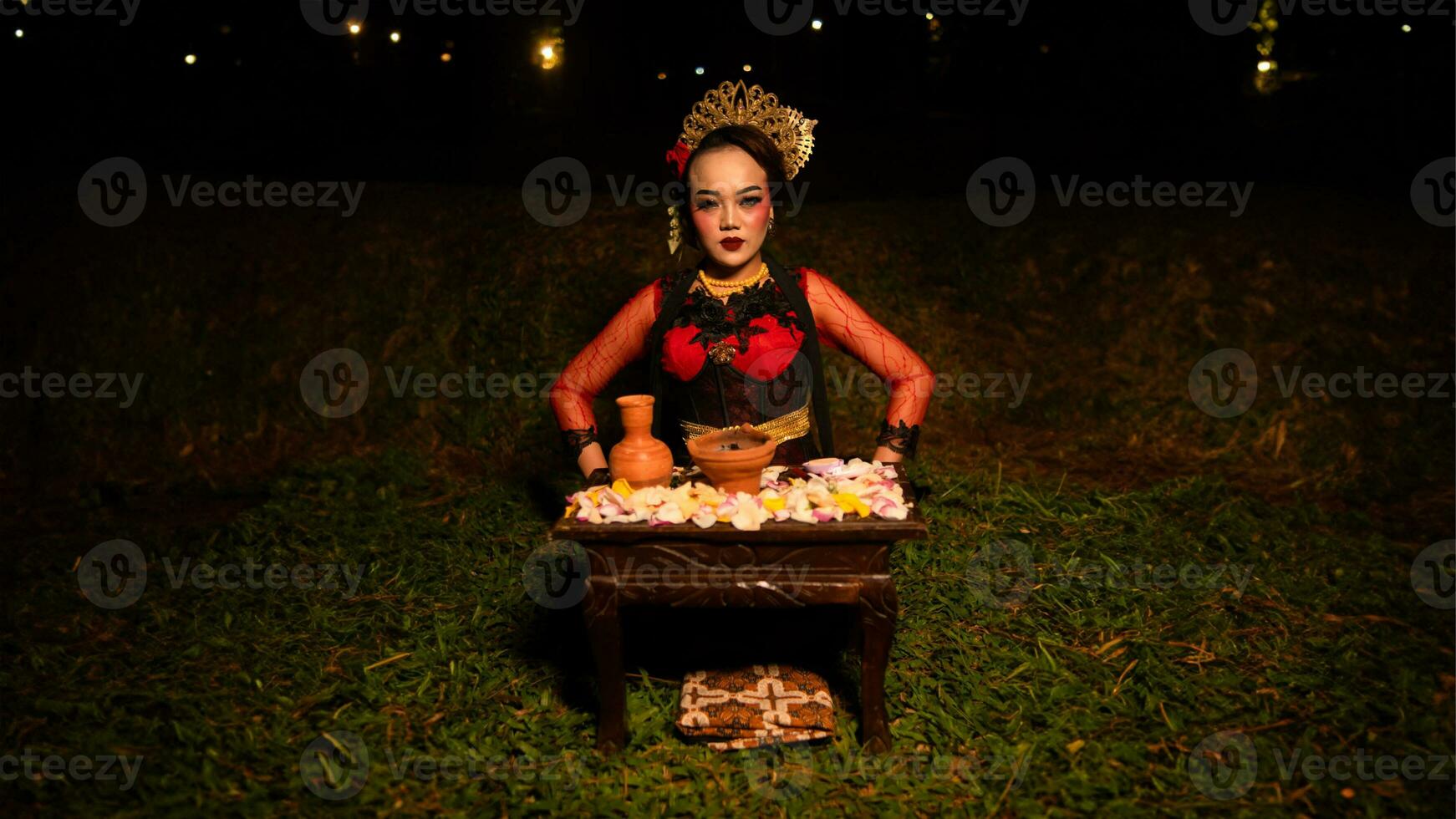 a female dancer looks focused on her ritual with a peaceful facial expression in front of offerings that look fresh and lively photo