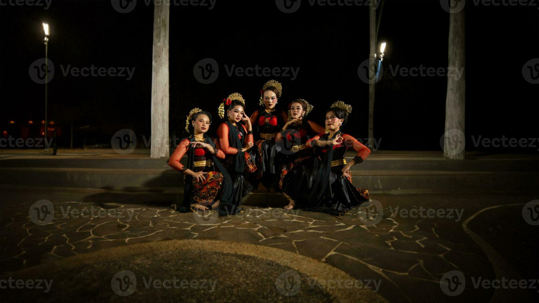 un grupo de indonesio bailarines sentado muy esmeradamente mientras vistiendo rojo vestidos en un castillo foto