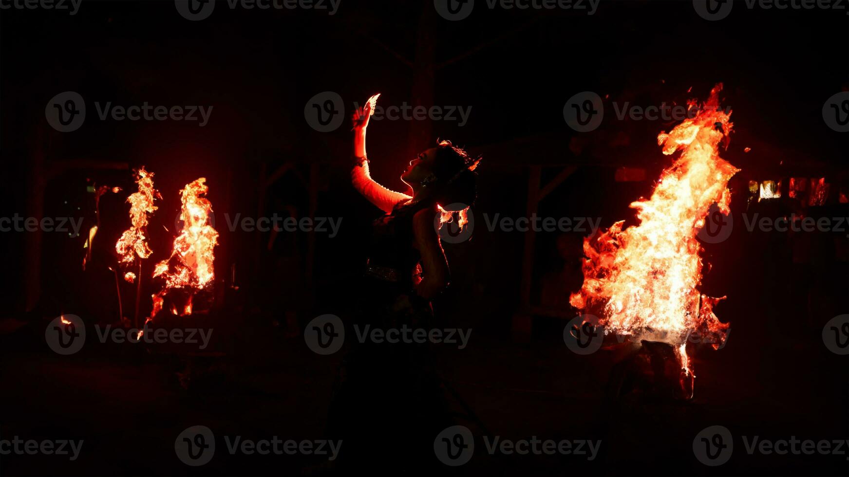 el silueta de un hembra bailarín participación joyería en el oscuro de noche es iluminado por el ligero de un ardiente fuego foto