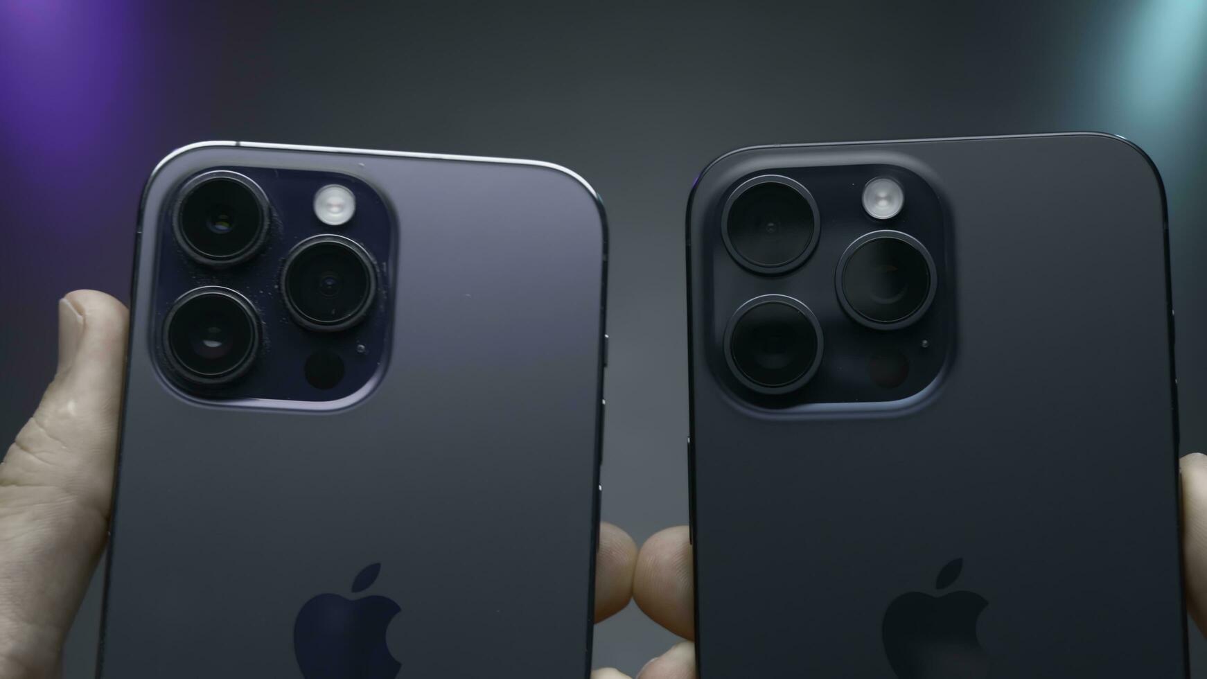 USA, New York - September 15, 2023. Comparison of design of iPhones 14 and 15 pro. Action. Comparison of latest iPhones 14 and 15 pro on isolated background. Person holds iPhones 14 and 15 pro in photo
