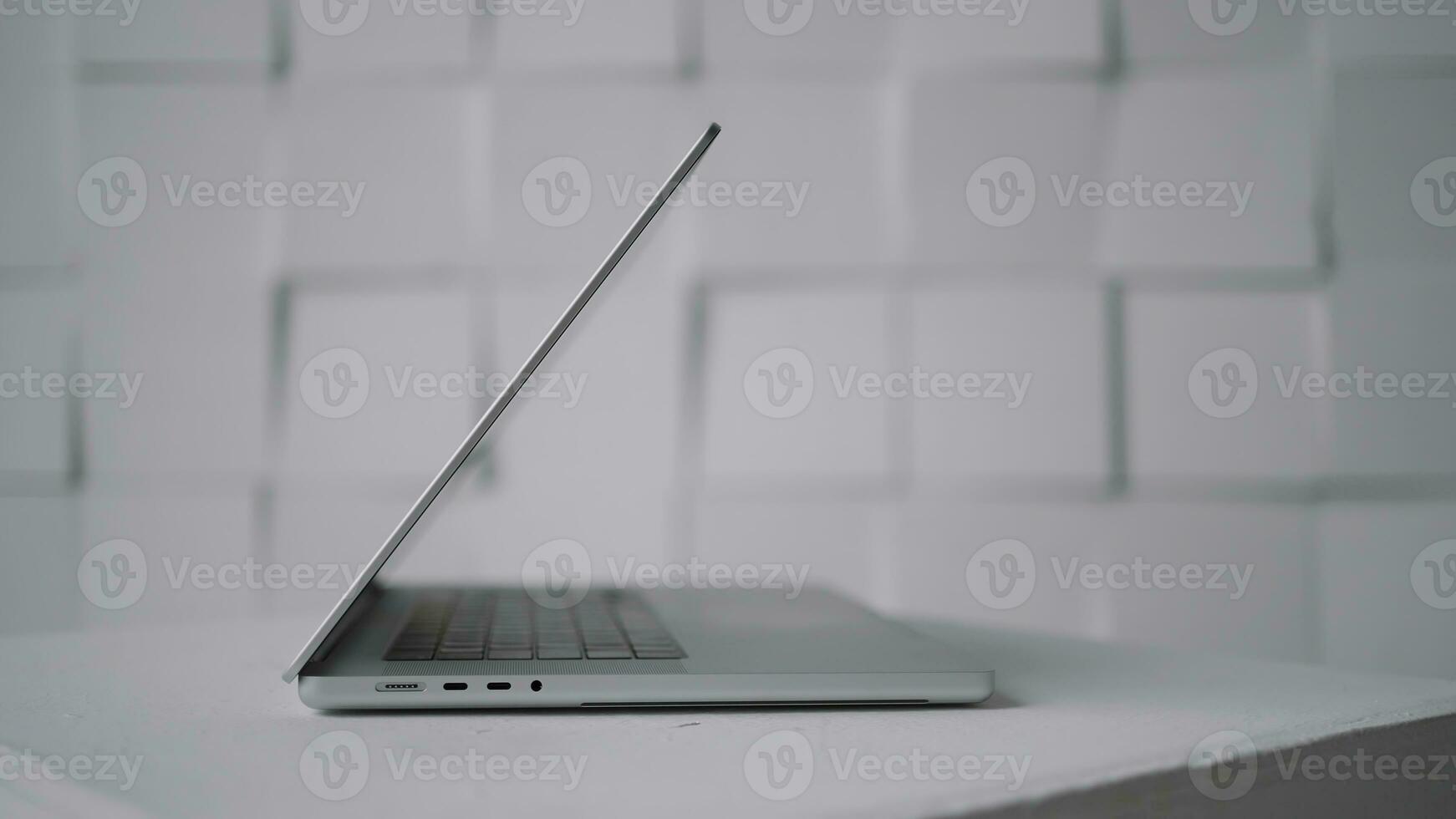 Side view of a new modern white laptop lying on a table surface against the wall. Action. Working from home, concept of freelance. photo