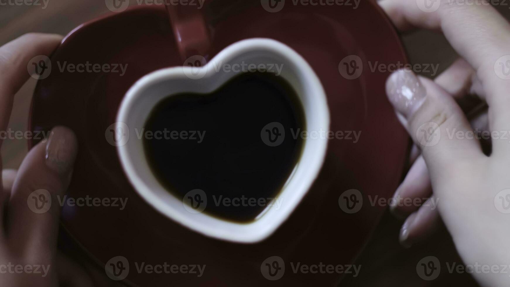 Woman made coffee in heart mug. Concept. Beautiful red heart-shaped mug with dark coffee. Romantic heart-shaped mug with coffee on romantic day photo