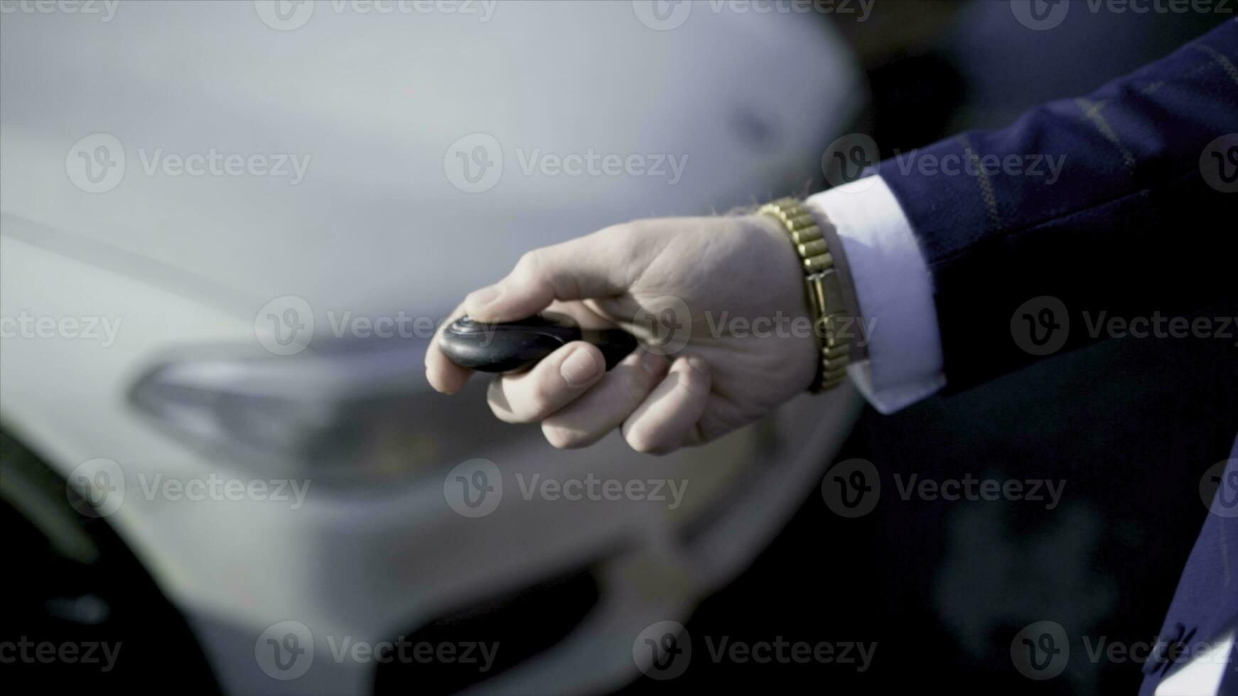 Close-up of businessman pressing car key. Action. Businessman opens car with electronic key and looks at phone. Modern car key to open and start it photo