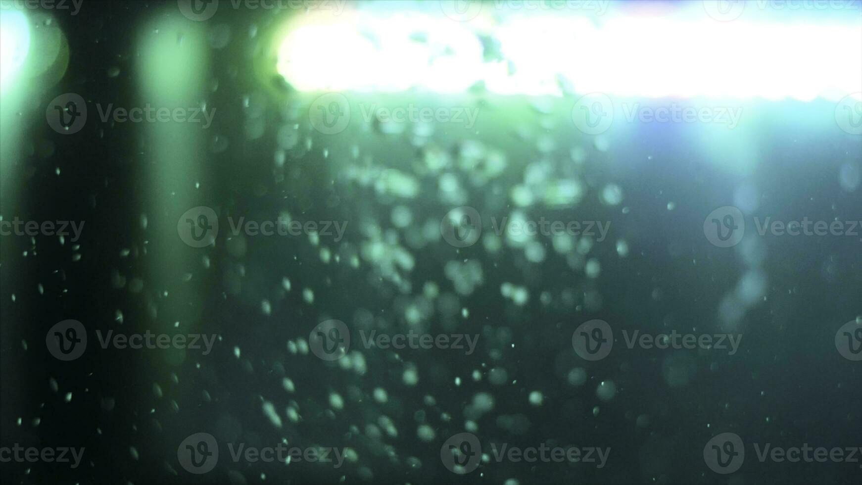 Side view of bubbling water with a green lamp on the background. Frame. Air bubbles underwater in empty fish aquarium. photo