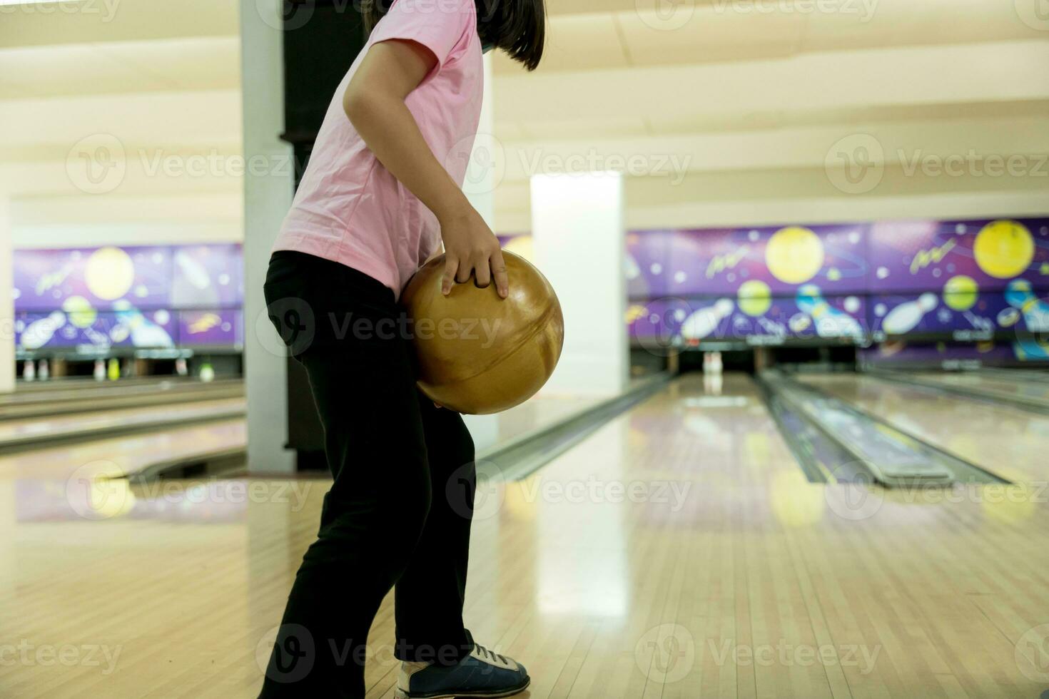 Young girl having fun with ball in bowling club. photo