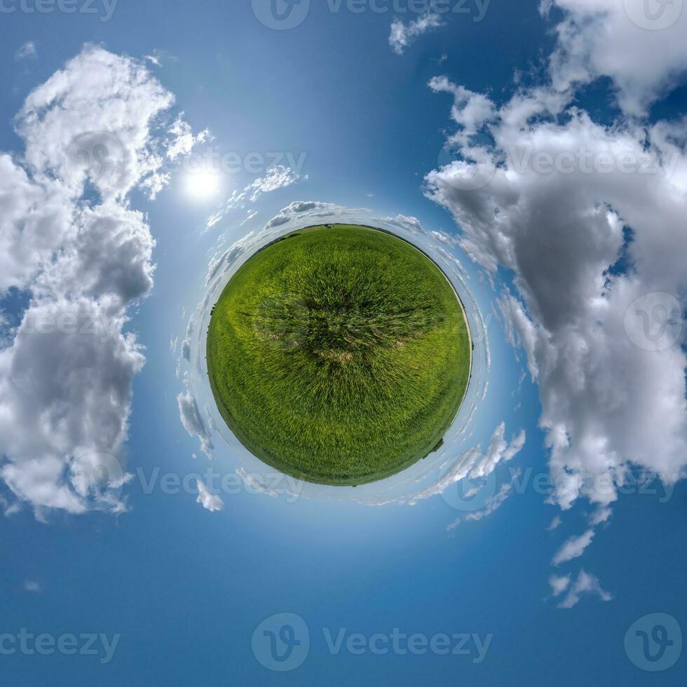 green tiny planet in blue sky with beautiful clouds. Transformation of spherical panorama 360 degrees. Spherical abstract aerial view. Curvature of space. photo