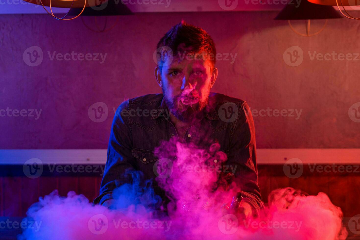 el hombre fumar un electrónico cigarrillo a el vape tienda. foto