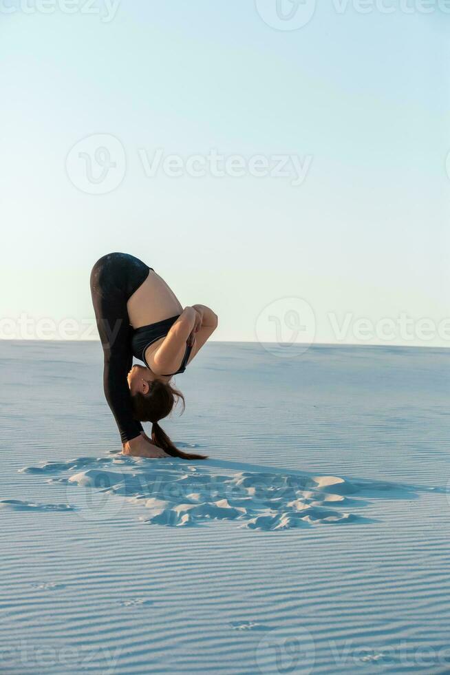 Fitness yoga woman stretching on sand. Fit female athlete doing yoga pose. photo